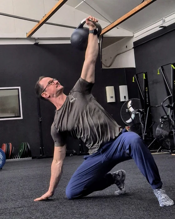 Bene in einer TGU-Phase mit erhobener Kettlebell und einer Hand am Boden